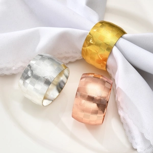 Three metal drum napkin rings in gold, silver and rose gold with diamond mesh texture