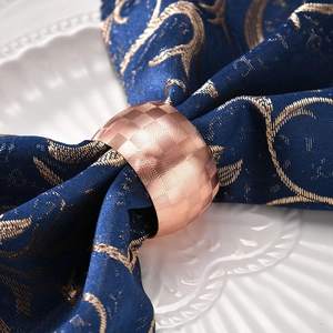Rose gold drum napkin ring with geometric diamond pattern on blue napkins