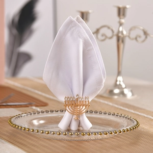 Elegant gold menorah napkin ring with sparkling rhinestones on a stylish glass dinner plate