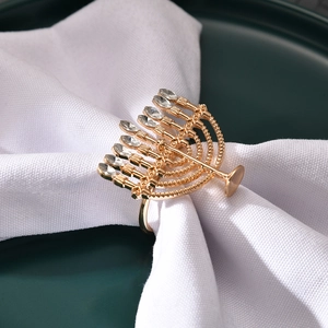 Golden Menorah napkin ring with crystals on white linen napkin and dark green plate