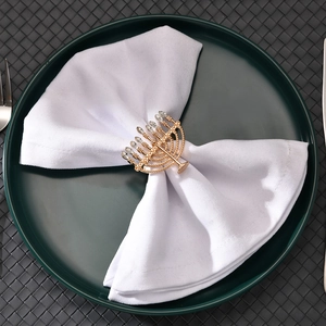 Close-up of golden Menorah napkin ring with crystals on a white napkin and green plate