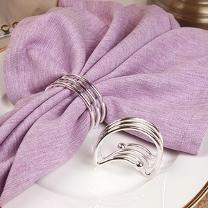 Modern silver triple-ring metal napkin holder set on a purple linen fabric