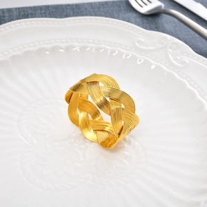 Gros plan d'un rond de serviette en métal doré tressé sur une assiette en céramique blanche