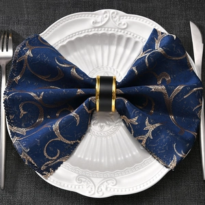 Eleganter schwarz-goldener Serviettenring auf blauem Stoff in edler Tischdekoration