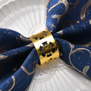 Golden snowflake cutout metal napkin ring on navy blue linen napkin for Christmas table