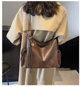 Detail der dunkelbraunen Hobo-Tasche aus Leder mit Seitentasche und rundem Anhänger