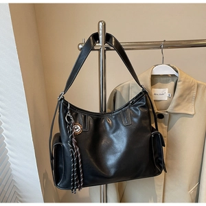 Detail der schwarzen Shopper-Tasche mit Kontrastnaht und modischem Anhänger am Bügel