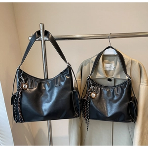 Detail der schwarzen Ledertasche mit Kontrastnähten und gewebtem Taschenanhänger