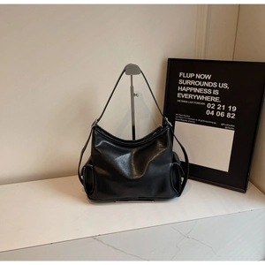 Detail einer schwarzen Ledertasche mit weißen Nähten und funktionalen Seitentaschen