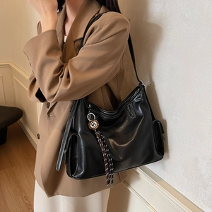 Schwarze Vintage-Einkaufstasche mit weißen Kontrastnähten und Quastendetails am Modell