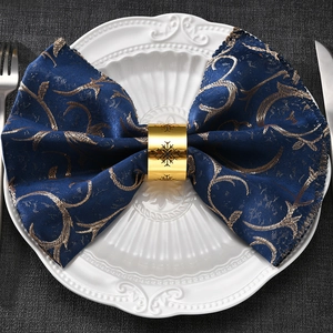 Golden snowflake napkin ring with hollow design on blue fabric napkin and white plate