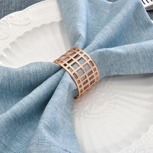 Modern geometric hollow napkin ring in rose gold finish on a blue linen napkin