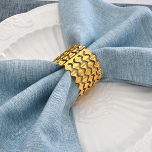 Elegant gold metal napkin ring with four-layer wavy hollow design on blue linen napkin