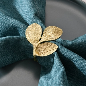 Golden leaf napkin ring with realistic vein textures on dark blue linen napkin