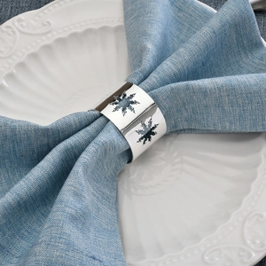 Elegant silver metal napkin ring with hollow snowflake pattern on blue napkin