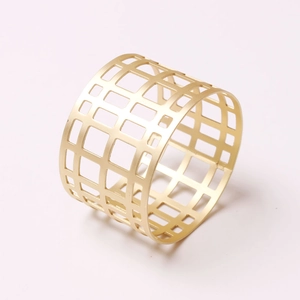Close-up of geometric hollow gold napkin ring with refined mesh metal texture