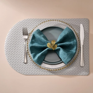 Elegant gold leaf napkin ring on dark green cloth with silver woven table mat