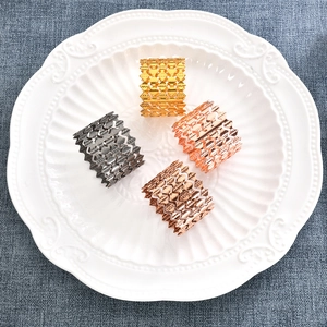 Macro detail of wave patterned hollow metal napkin rings in gold, silver, and rose gold