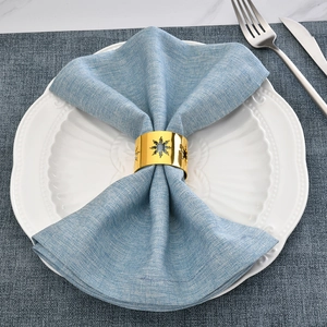 Close-up of gold snowflake napkin ring on a blue linen napkin with elegant table setting