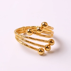Spiral multi-layer gold napkin ring with hammered texture and polished metal spheres