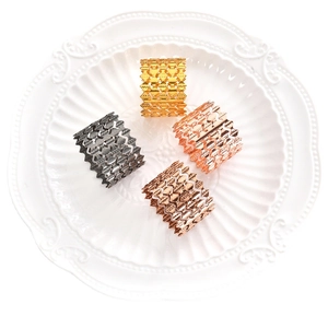 Set of four hollow wave pattern metal napkin rings in gold, rose gold, and gunmetal finishes