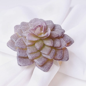 Dettaglio del portatovagliolo succulento con foglie sfumate e anello in rattan intrecciato