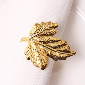 Elegant gold maple leaf napkin ring with detailed leaf veins on a white fabric napkin