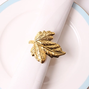 Golden maple leaf napkin ring featuring intricate leaf veins on a white ceramic plate