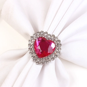Close-up of heart-shaped napkin ring with rose red crystal and silver metal base