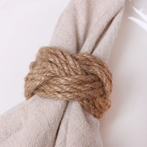 Handwoven natural jute napkin ring on a beige linen napkin against a white background