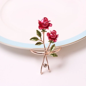 Detail of red rose napkin ring with green leaves and crystal stud on gold alloy