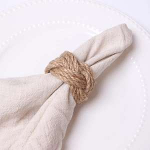 Handmade woven jute napkin ring with rustic knot design on white embossed dinner plate