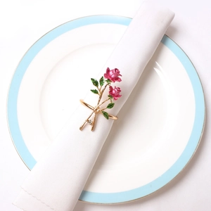 Detail of pink enamel rose napkin ring with crystal accent on a white plate