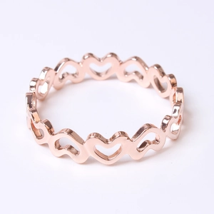Détail d'un rond de serviette ajouré en forme de cœur or rose au fini métallique poli