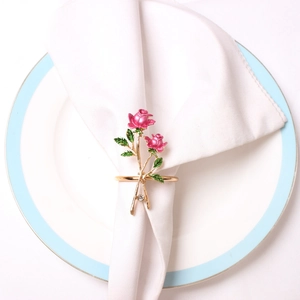 Detailed view of pink enamel roses and crystal napkin ring on white ceramic plate