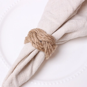 Detail of handmade brown jute rope napkin ring woven knot on white ceramic dinner plate