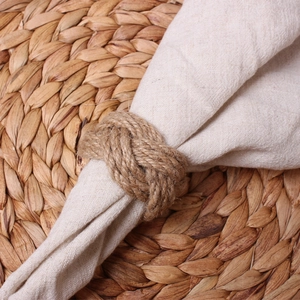 Macro detail of natural handmade braided jute rope napkin ring with sailor knot texture