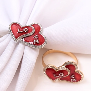 Close-up of heart-shaped napkin rings with red enamel and sparkling LOVE rhinestone inlay