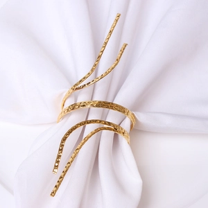 Modern gold spiral napkin ring with hammered metal texture on white fabric background