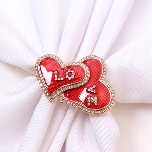 Detailed view of red enamel heart-shaped napkin rings with LOVE crystal lettering