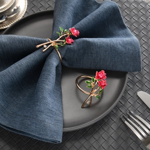 Elegant gold rose napkin rings with red flowers and crystals on a luxury table setting