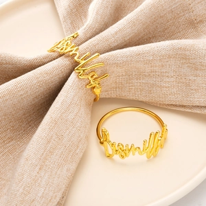 Custom gold zinc alloy cursive letter napkin rings on ceramic plate with linen fabric