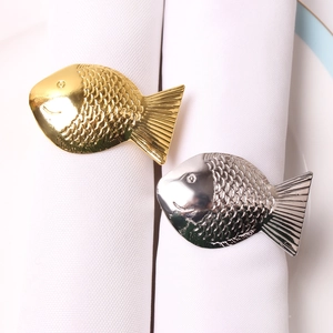Detailansicht von silbernen und goldenen Fisch-Serviettenringen mit Relief-Schuppen