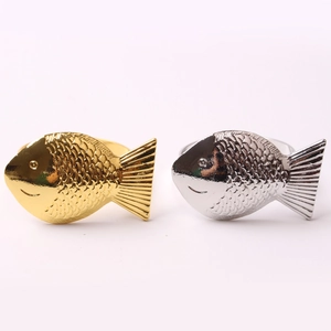 Golden and silver metal fish napkin rings with textured scales on a clean white background