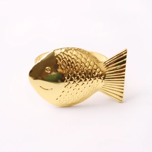 Makrodetail eines goldenen Serviettenrings in Fischform mit feinen Schuppenmustern
