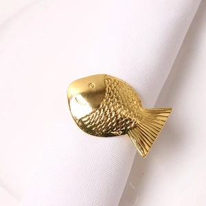 Detailansicht eines goldenen Serviettenrings in Fischform aus Metall auf Leinwand