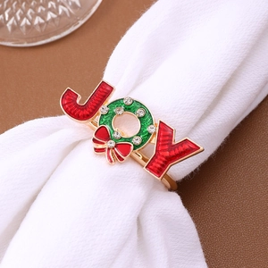 Christmas JOY napkin ring with green wreath and red bow on white napkin