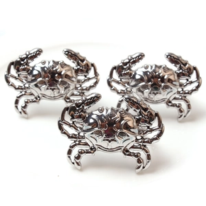 Three creative silver crab metal napkin rings with detailed shells on white background