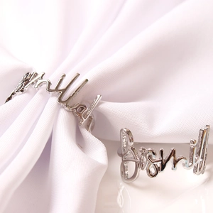 Custom silver cursive name rings featuring Hillary and David on white fabric and smooth surface