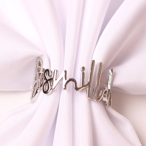 Macro detail of silver Bismillah metal napkin ring on white fabric for table decor